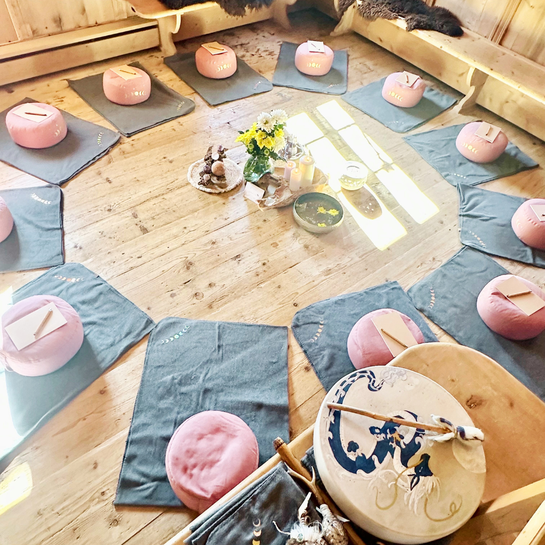 Runde Anordnung von pinken Kissen auf blauen Matten in einem hellen Raum.